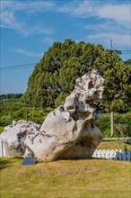 Huge white misshapen boulder on display in rock garden under blue cloudy sky in Gimcheon, South