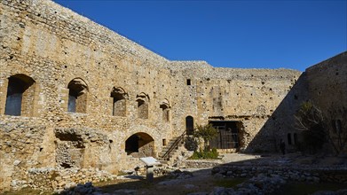 Walls of a historic fortress with arched windows under a clear sky, Chlemoutsi, High Medieval
