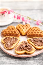 Homemade waffle with chocolate butter and cup of coffee on a gray wooden background. side view,