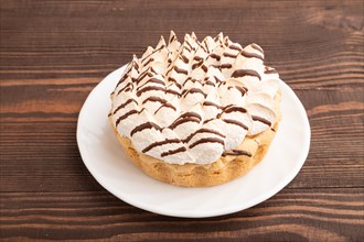 Tartlets with meringue cream and cup of coffee on brown wooden background. side view. Breakfast,