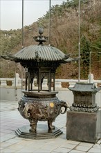 Ornate metal incense candle burner on patio of Guinsa temple building in South Korea