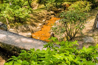 Small creek flowing under concrete footbridge in Japanese garden park in Hiroshima, Japan, Asia