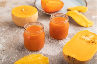 Baby puree with fruits mix, pumpkin, persimmon, mango infant formula in glass jar on brown concrete