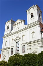 Baroque church with white facade and two towers against a clear blue sky, Roman Catholic Church of