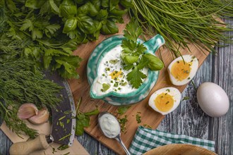 Herb dip in a turquoise ceramic jug, surrounded by fresh herbs and eggs