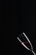 A champagne glass filled with rose sparkling wine against a black background