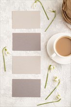 Gray paper business card mockup with spring snowdrop galanthus flowers and cup of coffee on gray