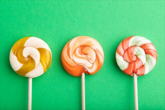 Three lollipop candies on green pastel background. copy space, top view, flat lay