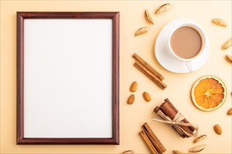 Composition with wooden frame, almonds, cinnamon and cup of coffee. mockup on orange background.