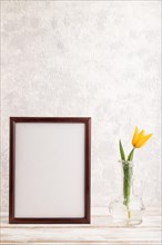Wooden frame with orange tulip flower in glass on gray concrete background. side view, copy space,