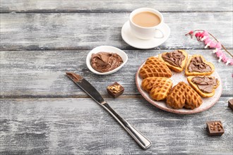 Homemade waffle with chocolate butter and cup of coffee on a gray wooden background. side view,