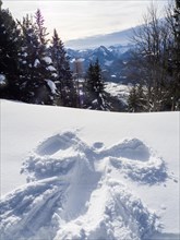 Winter atmosphere, snow-covered landscape, snow-covered Alpine peaks, angel figure in the snow,