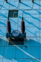 High voltage power lines with ceramic insulators on side of power transfer station building