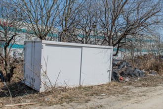 White metal storage container sitting on front of treeline in rural industrial area