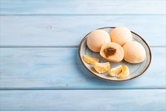 Japanese rice sweet buns mochi filled with tangerine jam on a blue wooden background. side view,