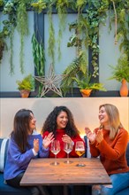 Women celebrating and applauding while drinking wine in a restaurant