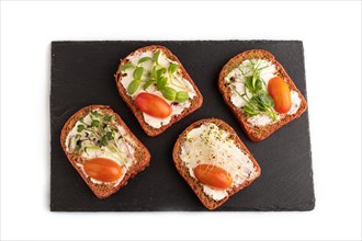 Red beet bread sandwiches with cream cheese, tomatoes and microgreen on black board isolated on