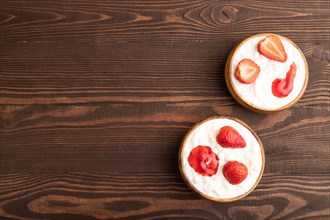 Grained cottage cheese with strawberry jam on brown wooden background. top view, flat lay, copy