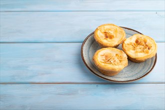 Traditional portuguese cakes pasteis de nata, custard small pies with almonds on blue wooden