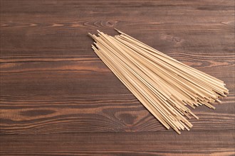 Japanese buckwheat soba noodles on brown wooden background. Side view, copy space