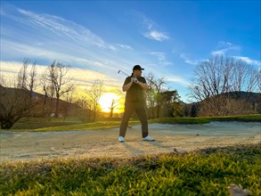 Golfer and Golf Ball in a Sand Trap on Golf Course in Sunset in a Sunny Day in Switzerland