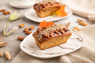 Caramel and almond cake with cup of coffee on brown concrete background and linen textile. side