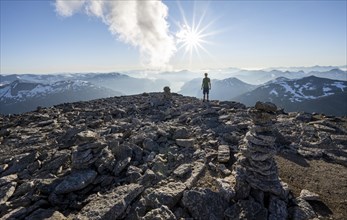 Mountaineer on the summit of Skala with cairn, view of mountain landscape and fjord Faleidfjorden,