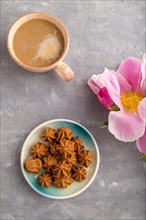 Homemade soft caramel fudge candies on blue plate and cup of coffee on gray concrete background,