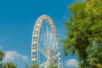 Ferris wheel rising into a blue sky with wispy clouds