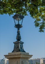 Ornate vintage street lamp against a clear blue sky in a city setting