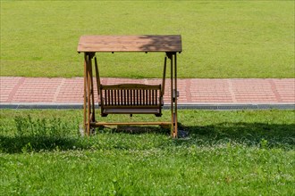 Rear view of wooden swing park bench beside walkway in South Korea