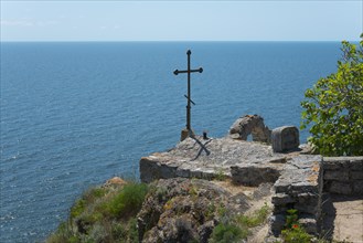 A simple cross overlooks the calm sea from a rocky cliff, Chapel of St Nicholas, Cape Kaliakra,