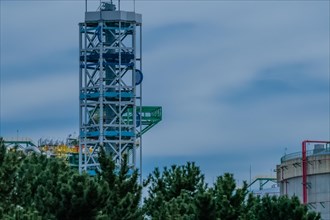 Platform tower at a gasoline storage facility on a cloudy day with pine trees in the foreground