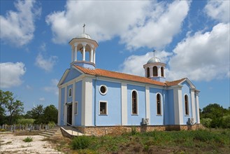 A small church with blue walls and white domes under a clear blue sky surrounded by nature, Sveti