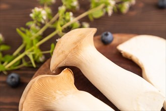 King Oyster mushrooms or Eringi (Pleurotus eryngii) on brown wooden background with blueberry,