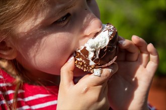 Seven-year-old girl eats a chocolate kiss at a folk festival
