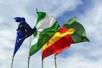 Four flags next to each other, fluttering in the wind, strong wind, European Union, Andalusia,