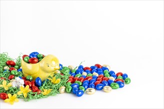 Chocolate eggs and a decorative chick surrounded by artificial grass as a festive decoration, white