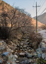 Small rocky stream bed running next to rural country road in South Korea