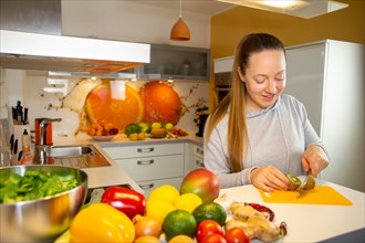 Vegan nutrition: Young woman cuts a kiwi
