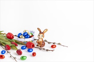Easter composition with an Easter bunny and a bowl full of chocolate eggs, white background, copy