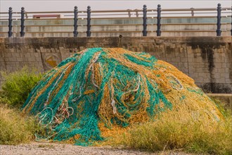 Large ball of yellow and green fishing nets in front of sea wall on cloudy day in South Korea