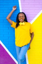 Vertical portrait of a young african woman smiling at camera next to colorful urban wall