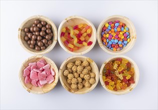 Symmetrical arrangement of different sweets in round bowls on a white background