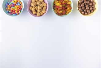Bowls of colourful sweets on a light background, arranged at the edge of the picture