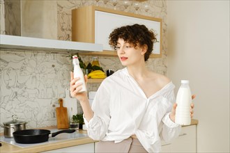 A modern young woman chooses between natural organic milk and industrial milk