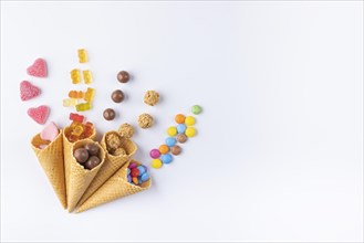 Colourful sweets arranged in ice cream cones on a white background, copy room
