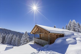 Alpine hut in winter with sun, snow, sunbeams, Hoernle-Alm, Ammergau Alps, Upper Bavaria, Bavaria,