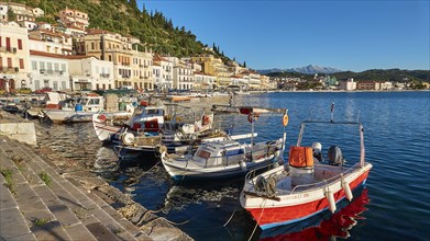 Small fishing boats at a sun-drenched Mediterranean harbour with mountains, Taygetos Mountains,