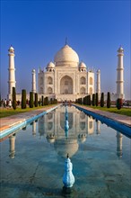 Symmetrical view of the Taj Mahal with its reflection in the water under a clear blue sky, Taj